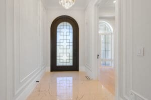 Elegant hallway with a decorative glass door and polished marble floor.