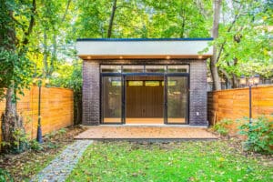 Modern garden office with glass doors surrounded by greenery.