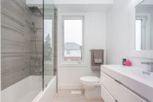 Bright modern bathroom with glass shower and white fixtures.