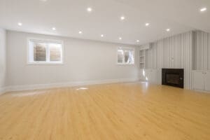 Spacious, empty room with wooden flooring and recessed lighting.