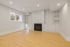 Empty room with wooden floor and built-in white shelves.