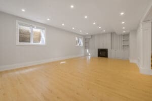 Spacious empty room with wooden floors and recessed lighting.