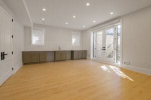 Bright, spacious empty room with wooden flooring and large glass doors.