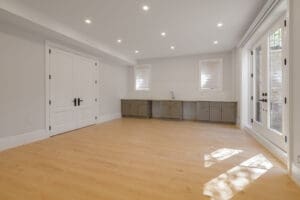 Bright empty room with wood flooring and large windows.