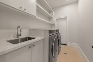 Modern laundry room with washer, dryer, and ample white cabinetry.
