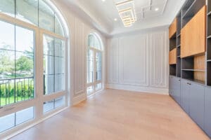 Bright empty room with large arched windows and light wood flooring.