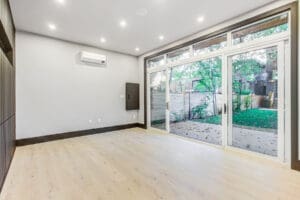 Bright empty room with wooden floors and large glass doors.