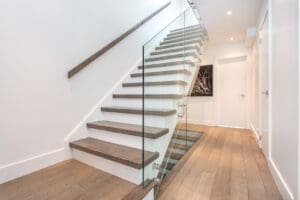 Modern staircase with glass railing and wooden steps in a bright home.