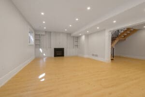 Spacious, empty room with wooden floor and recessed ceiling lights.