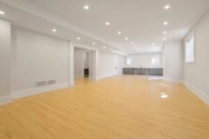 Spacious, modern open-plan room with wooden floors and recessed lighting.