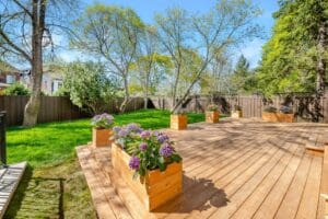 Sunny backyard with wooden deck and flower planters.