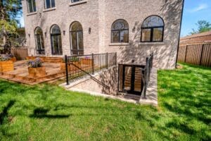 Sunlit yard with basement entrance and large windows in a stone building.