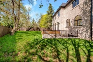 Sunny backyard with green lawn and a stone house.