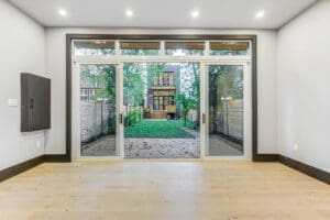 Modern room with large glass doors opening to a green backyard.