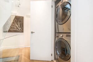 Stacked washer and dryer inside a small closet in a modern home.