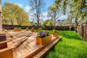 Sunny backyard with wooden deck and flower planters.