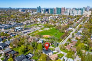 Aerial view of a suburban neighborhood with a park and city skyline.