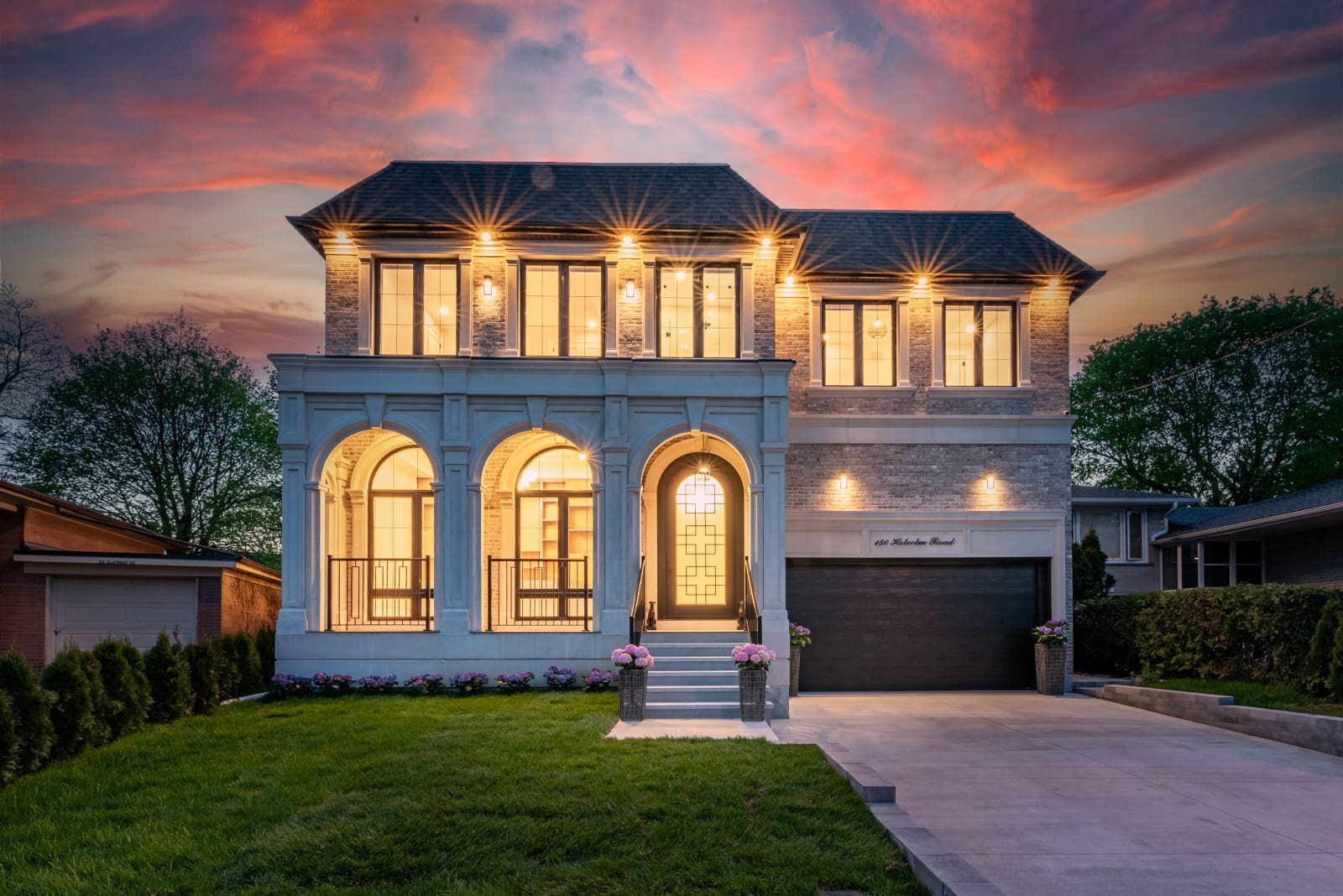 Elegant two-story house with warm lighting at sunset.