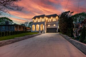 Elegant house with warm lights at sunset and a wide driveway.