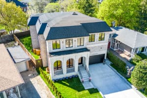 A large modern two-story brick house with a spacious driveway and green lawn.