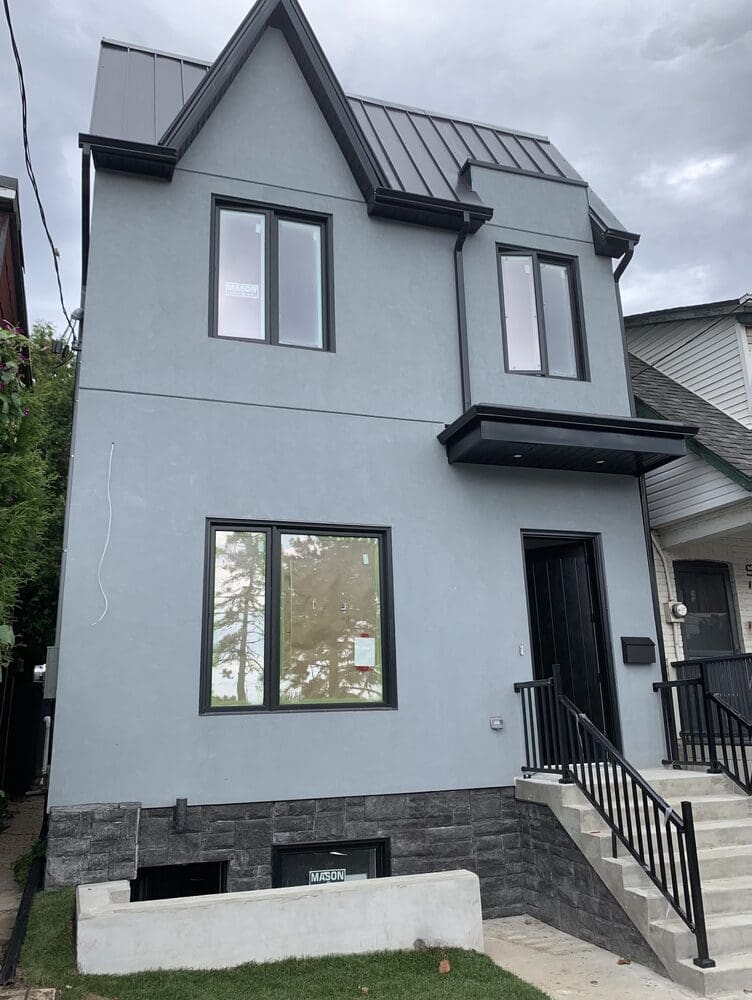 A modern two-story gray house with black trim and a small front porch.