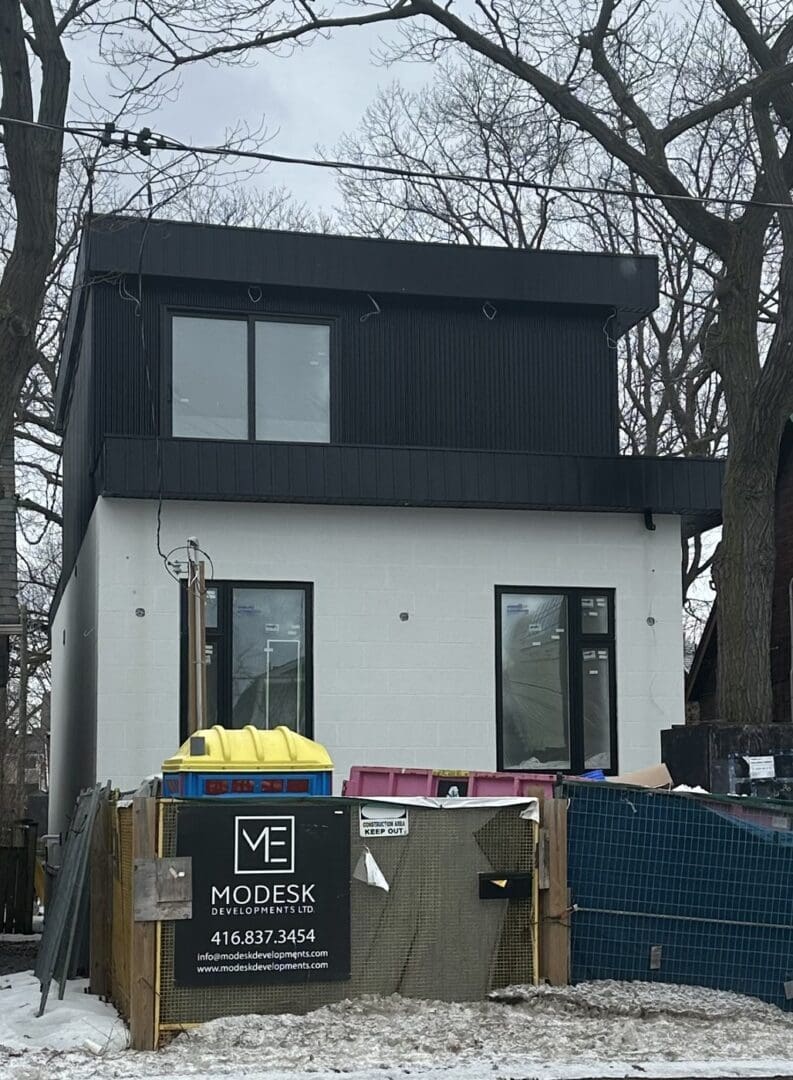 Modern two-story house under construction with black exterior and large windows.