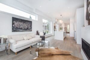 Bright modern living room with white sofas and large artwork.