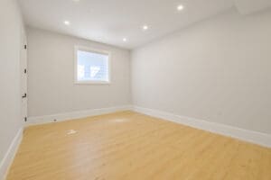 Empty room with wooden floor and small window.