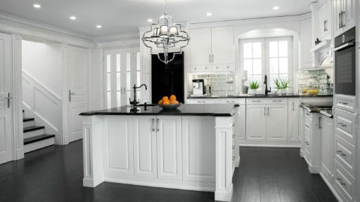 Modern white kitchen with black countertop island and chandelier.